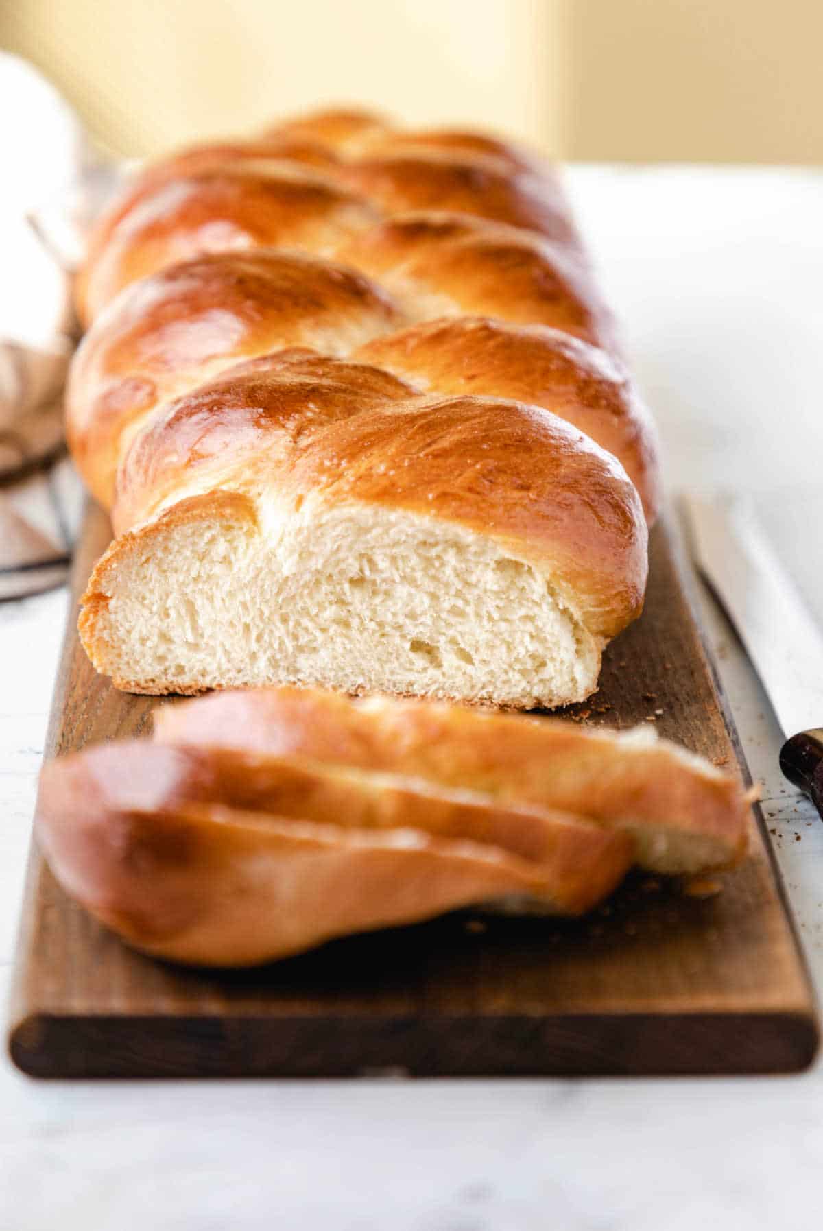 A loaf of braided bread with three slices cut off.