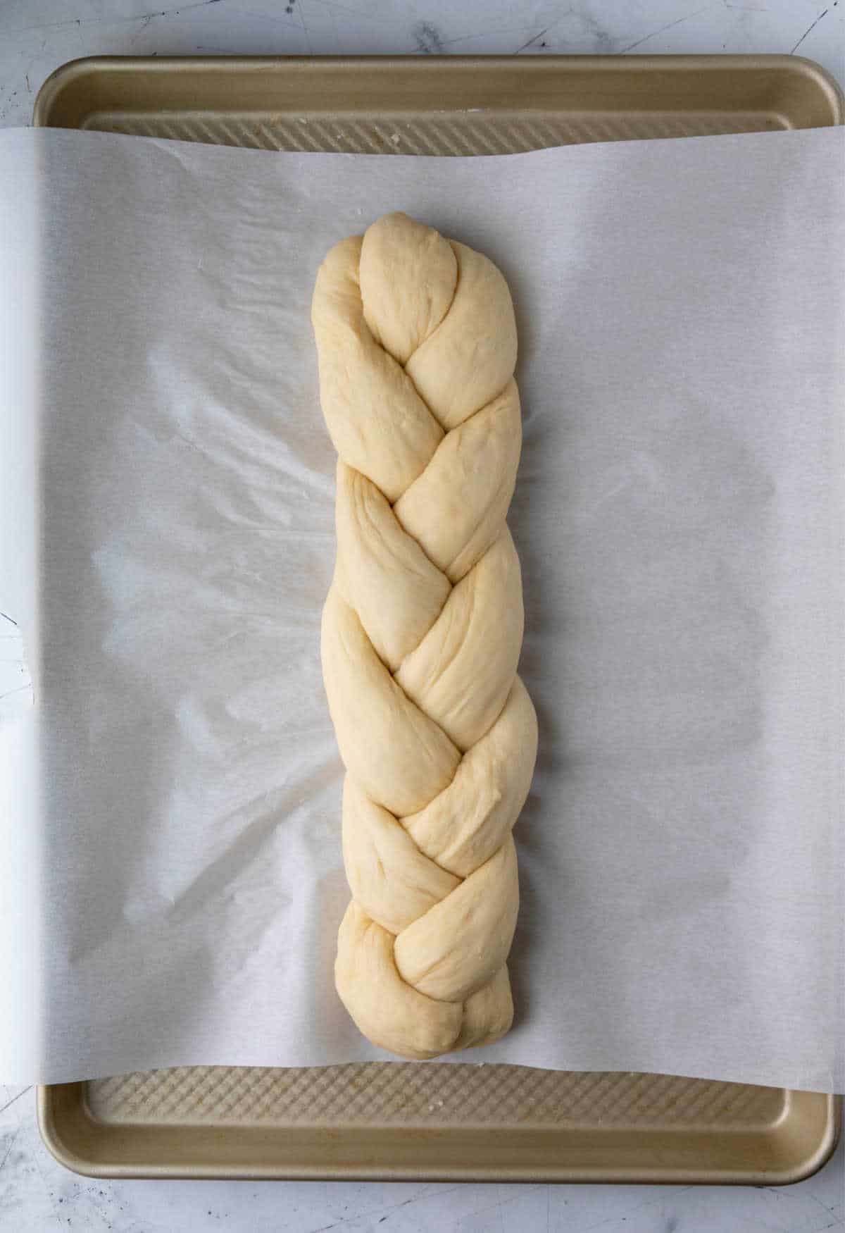 A loaf of unbaked braided bread on a baking sheet.
