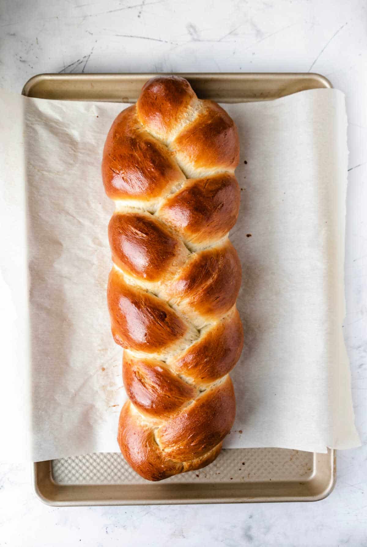 A loaf of baked braided bread on a baking sheet. 