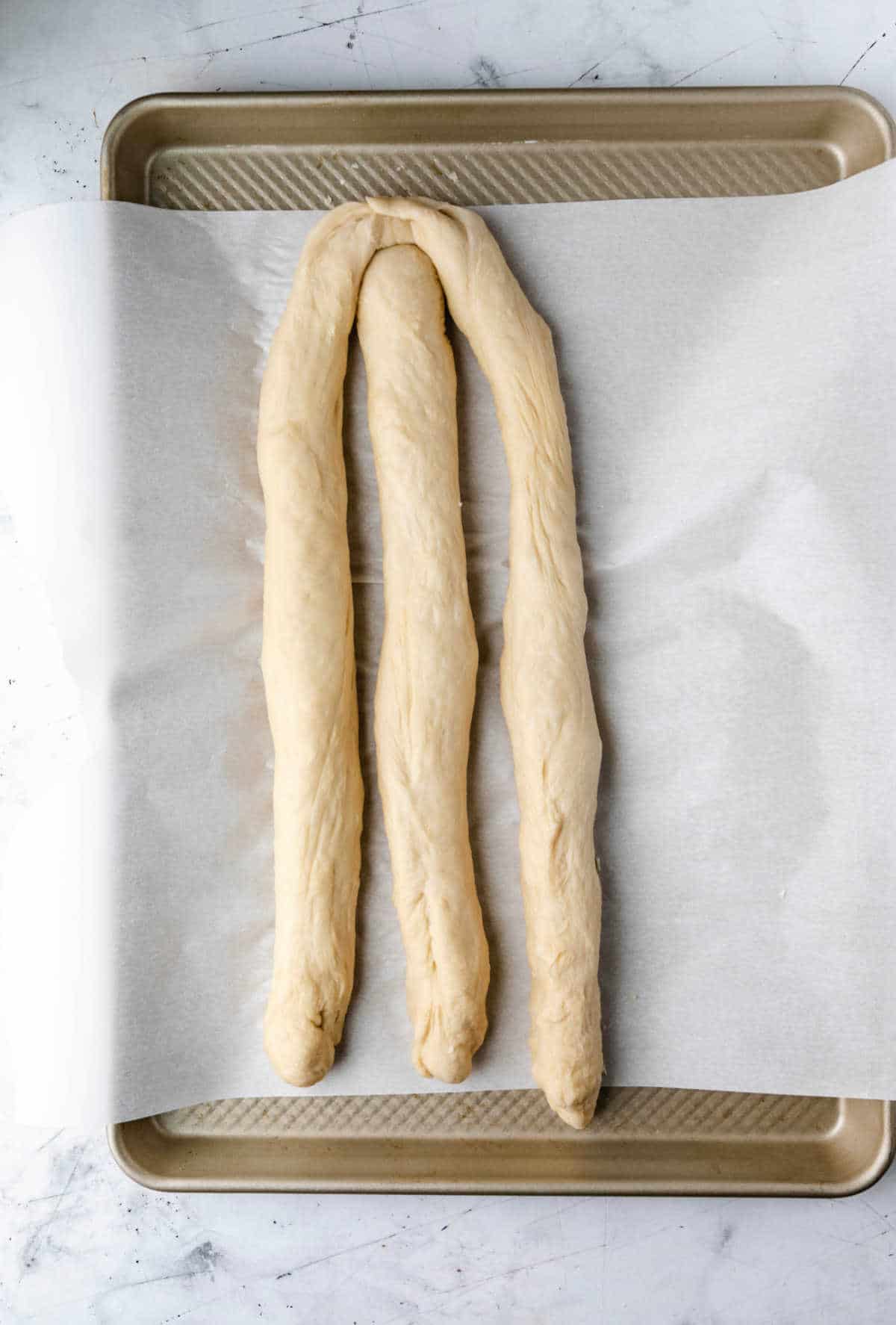 Three dough strands with one end pinched together. 