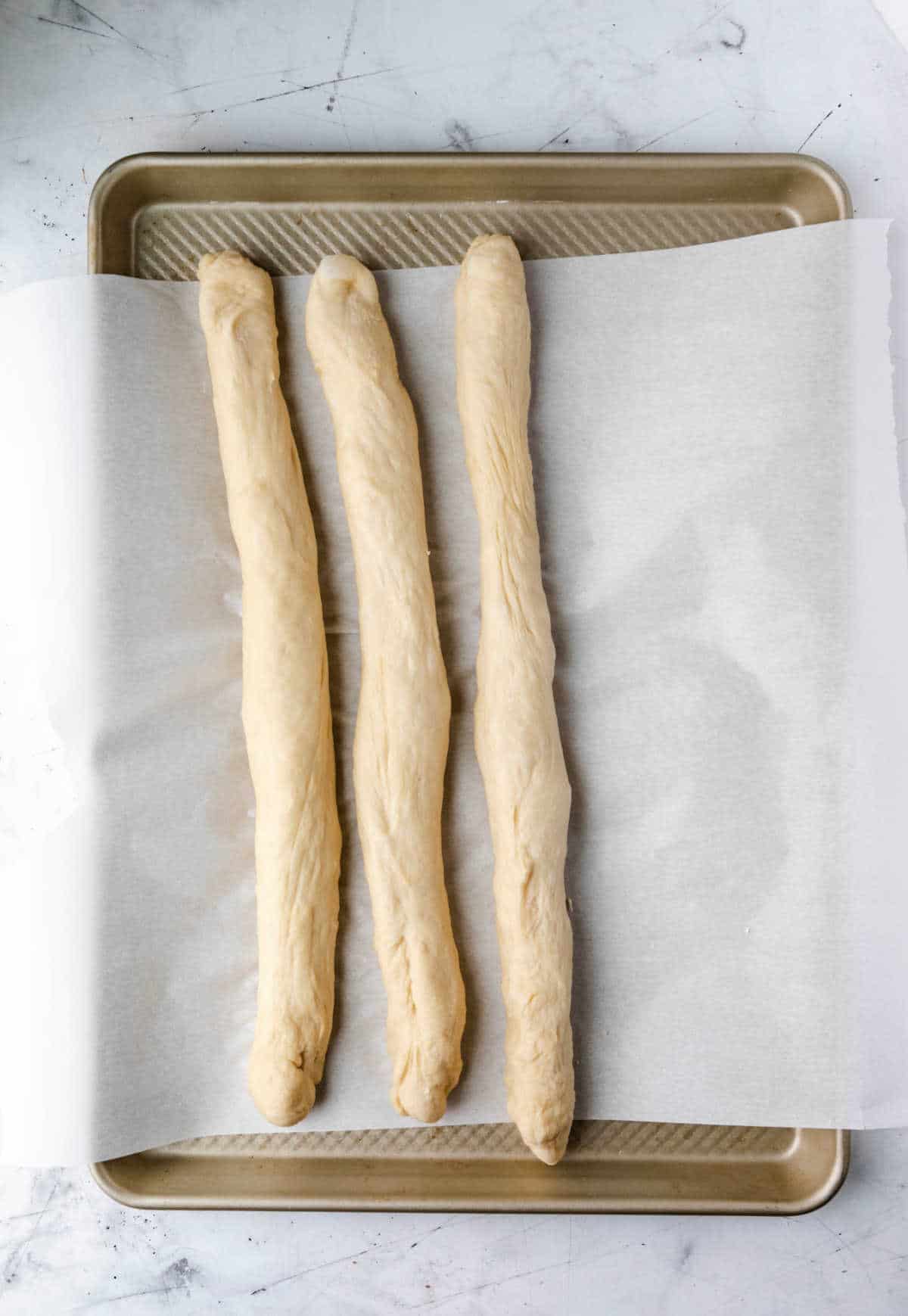 Three ropes of dough on a baking sheet. 
