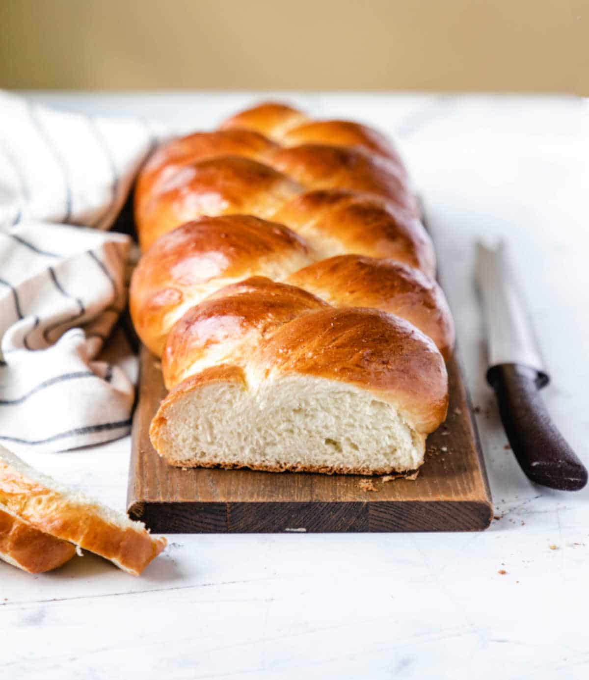 A loaf of braided bread next to a striped kitchen towel. 