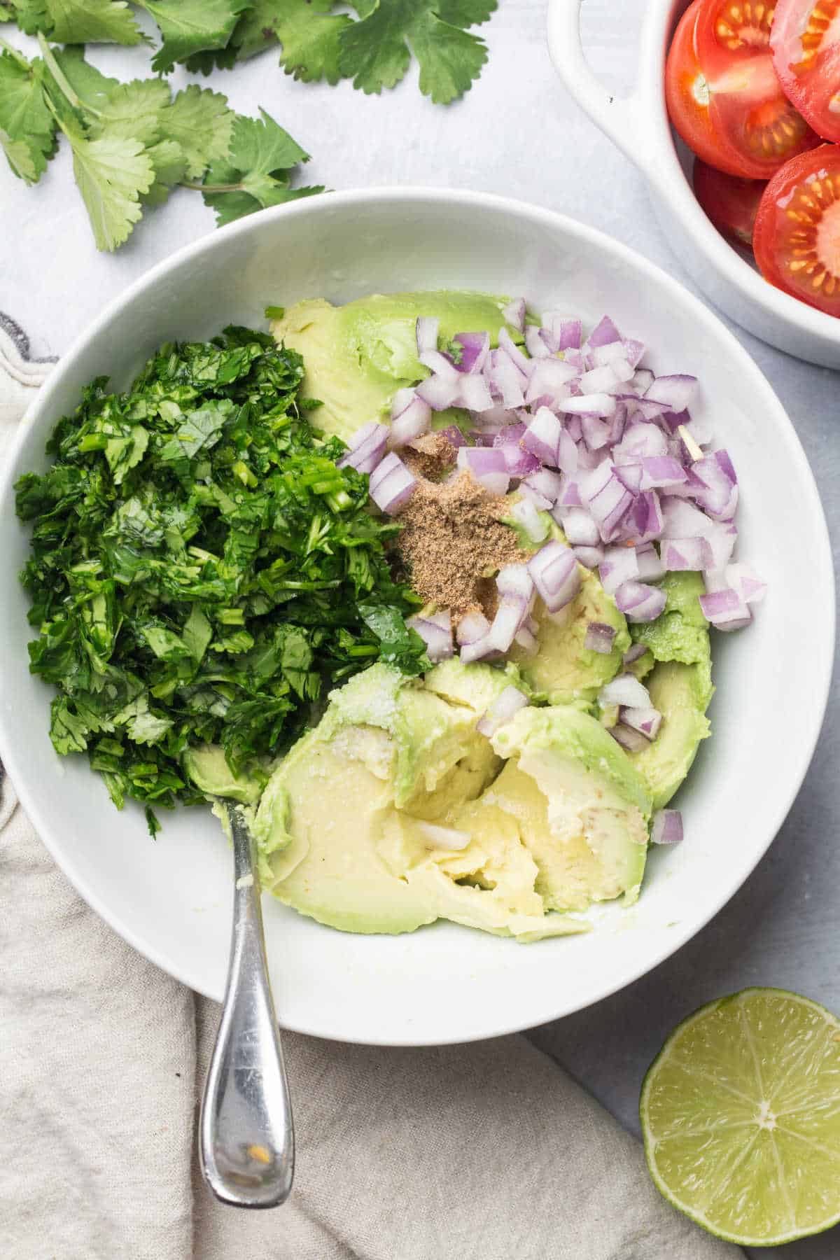 Ingredients for guacamole in a dish with a spoon.