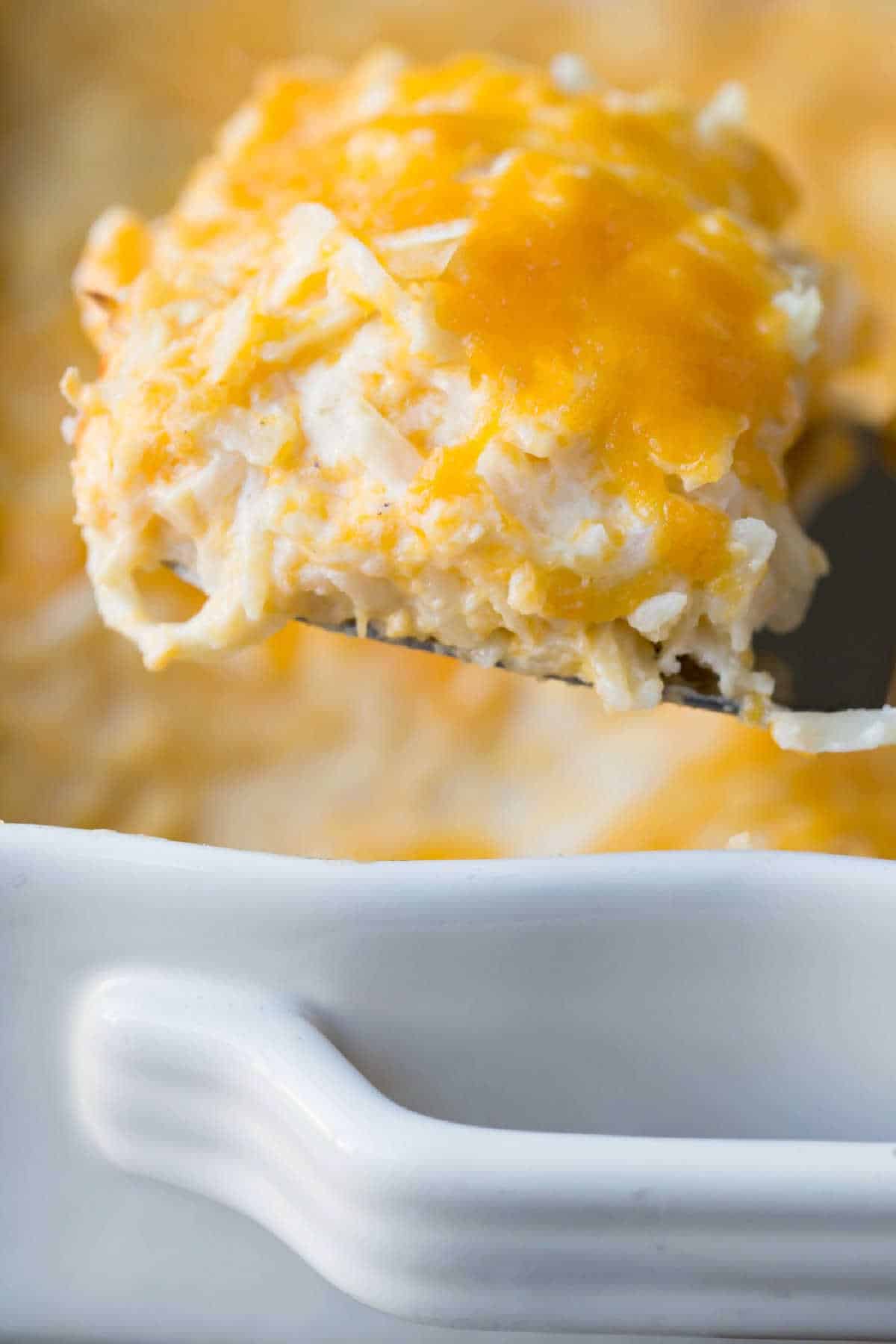 Scoop of funeral potatoes on a metal spatula.