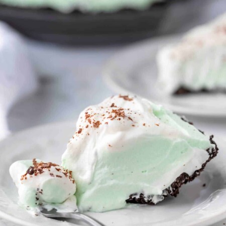 A slice of grasshopper pie on a white plate with a fork taking a bite.