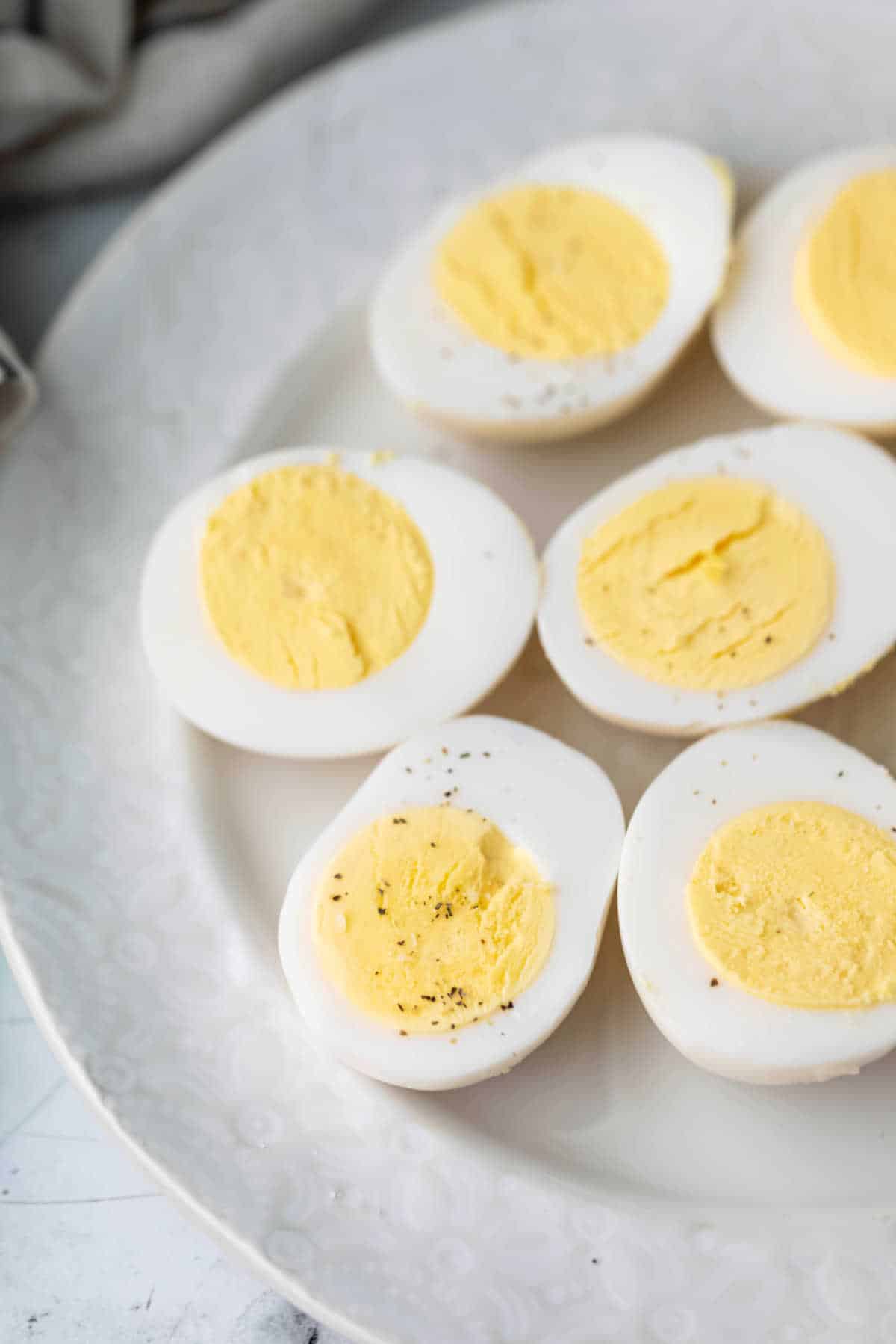 Hard boiled eggs sliced in half on a white plate. 