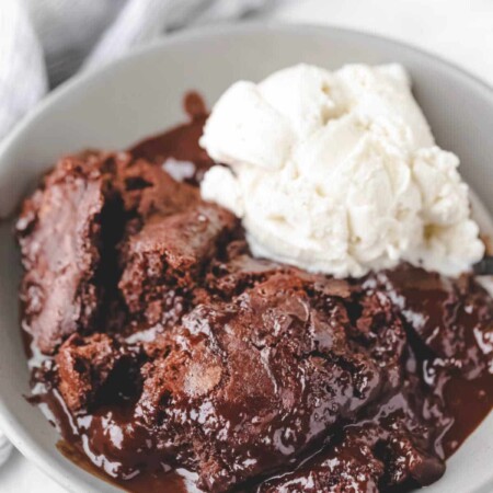 A bowl of hot fudge cake with a scoop of vanilla ice cream.