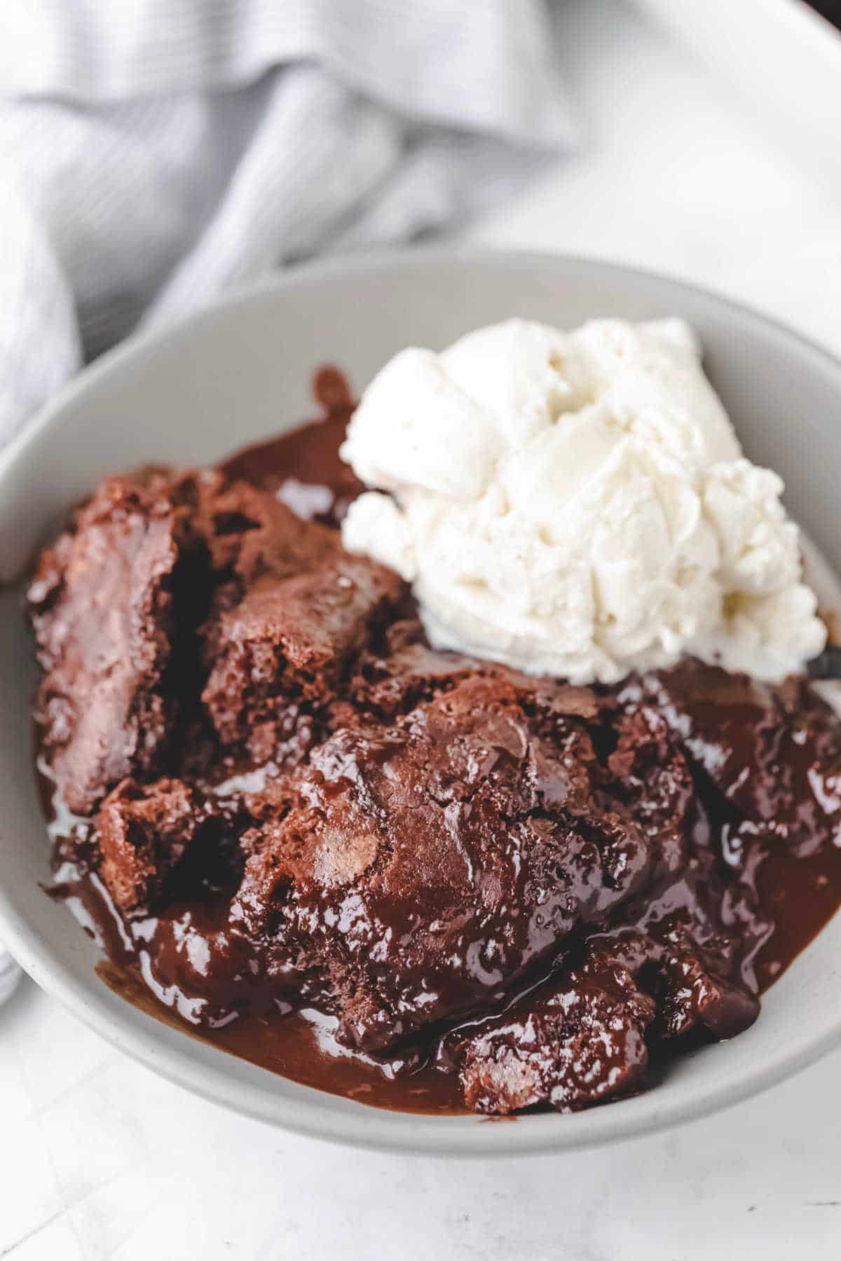 A bowl of hot fudge cake with a scoop of vanilla ice cream. 