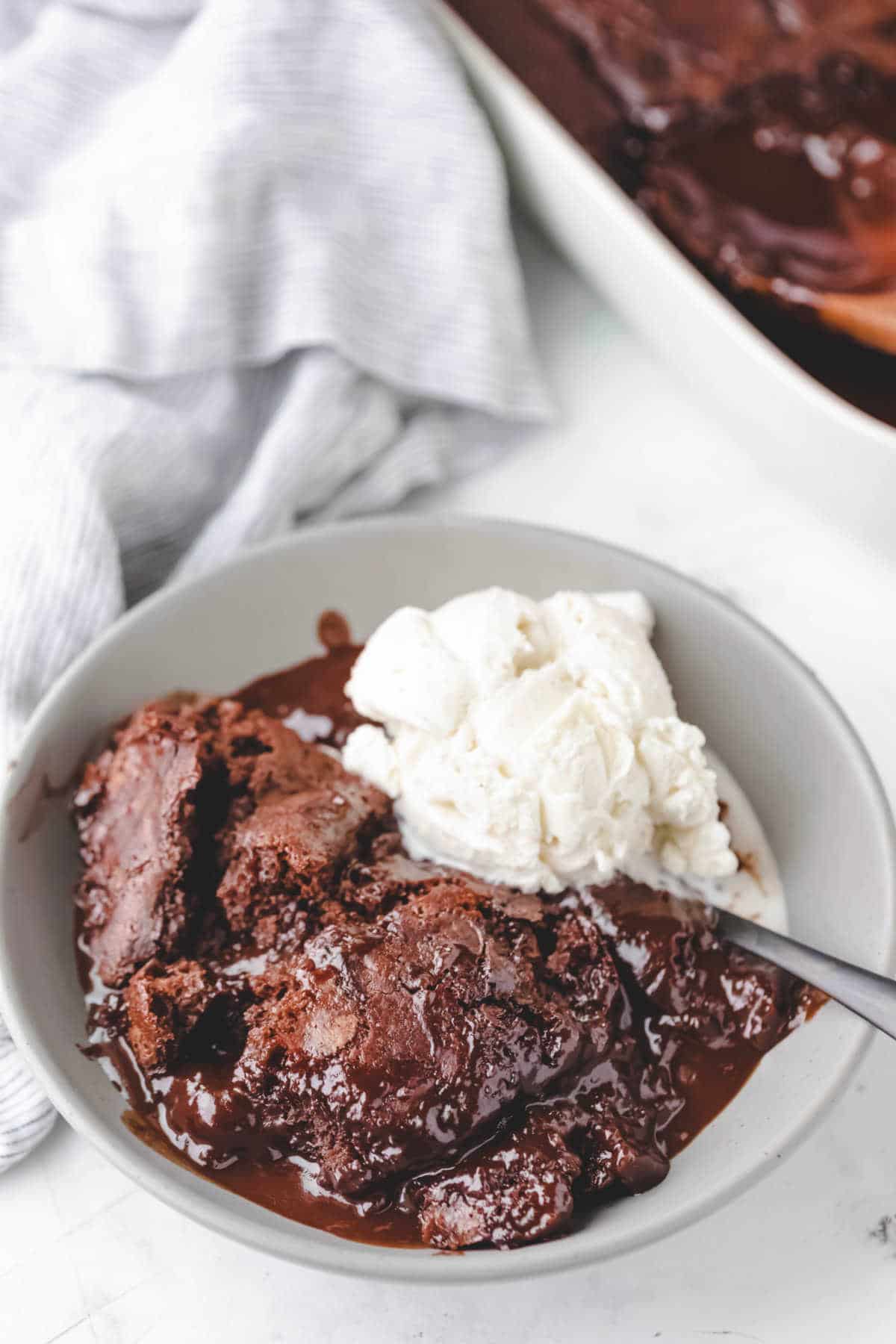 A bowl of hot fudge pudding cake next to the baking pan.