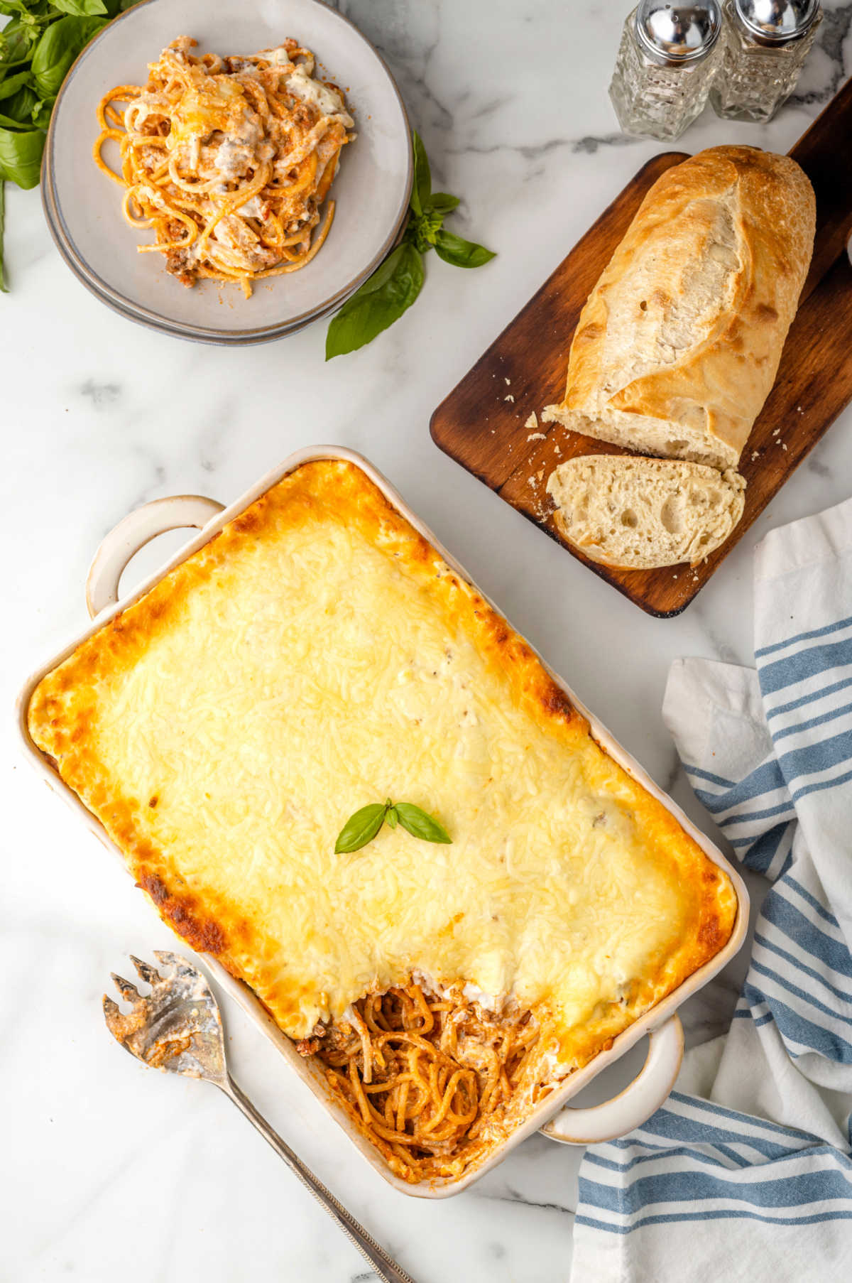 Baked spaghetti casserole next to a loaf of bread. 