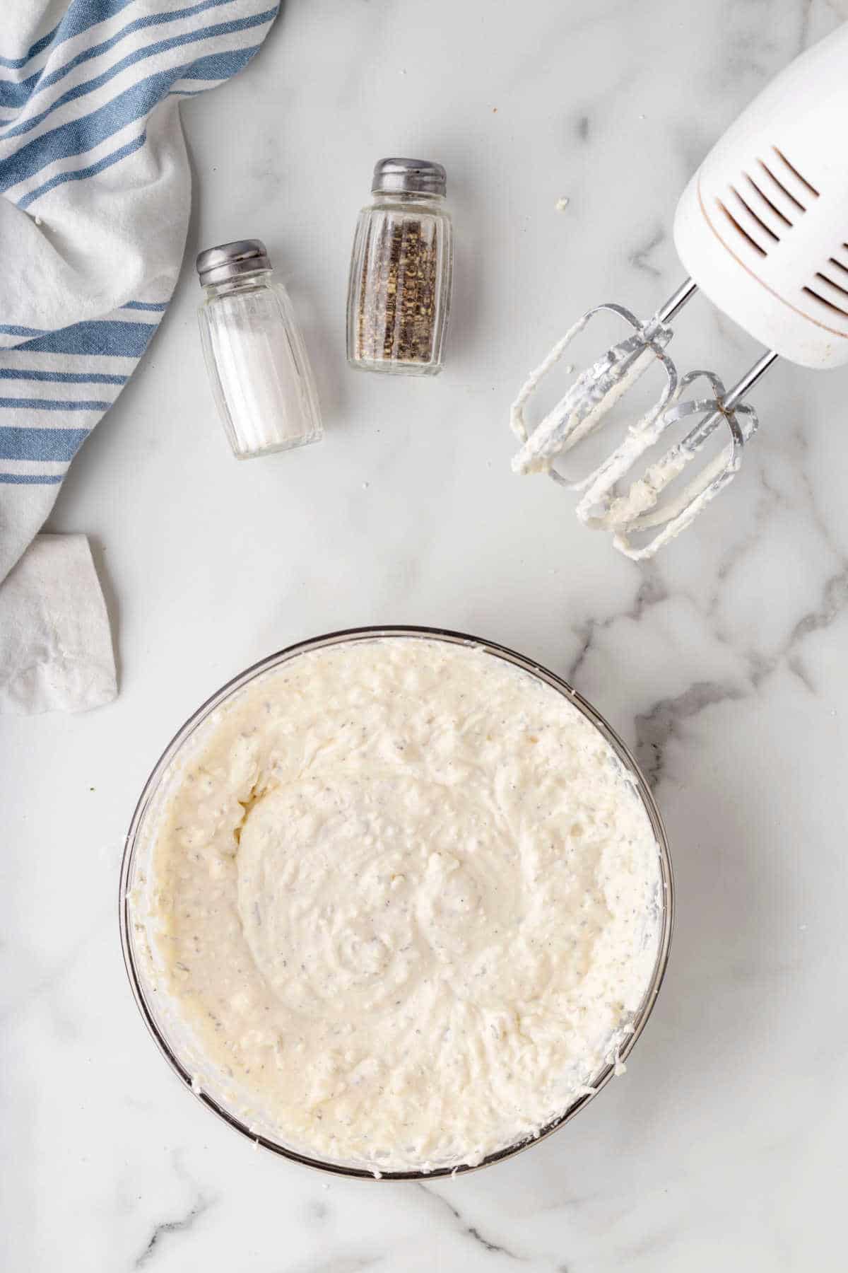 Cream cheese ricotta and spices in a mixing bowl. 