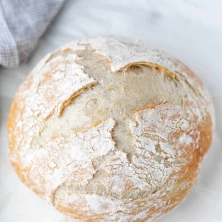 A loaf of no knead bread on a marble background.