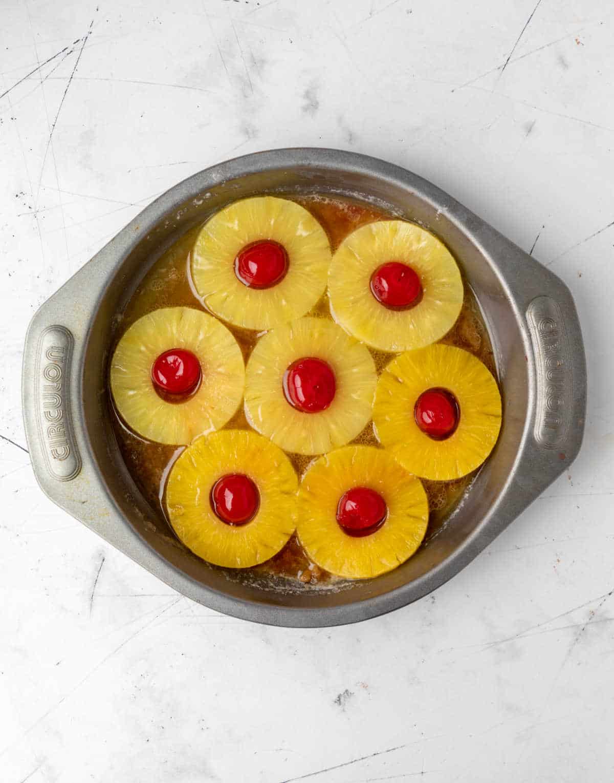 A pan with maraschino cherries in pineapple slices.