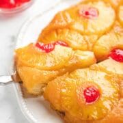 A knife removing a piece of pineapple upside down cake.