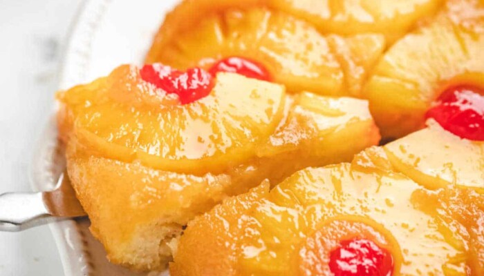 A knife removing a piece of pineapple upside down cake.