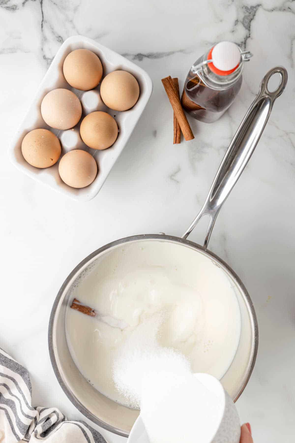 Milk sugar and cinnamon stick in a silver saucepan.