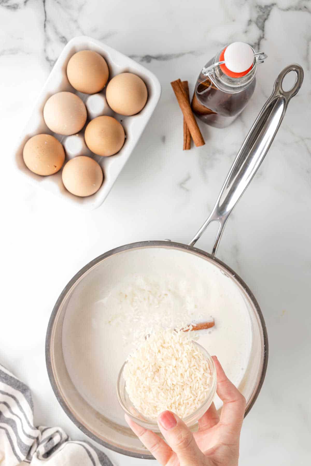 Rice pouring in a saucepan of milk and sugar. 