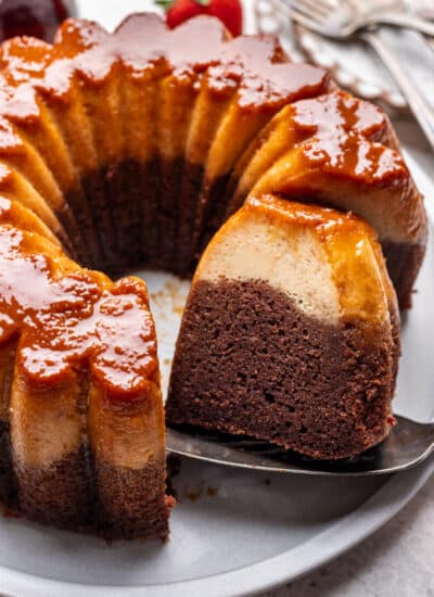 A cake server holding a slice of chocoflan next to the cake.