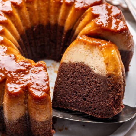 A cake server holding a slice of chocoflan next to the cake.