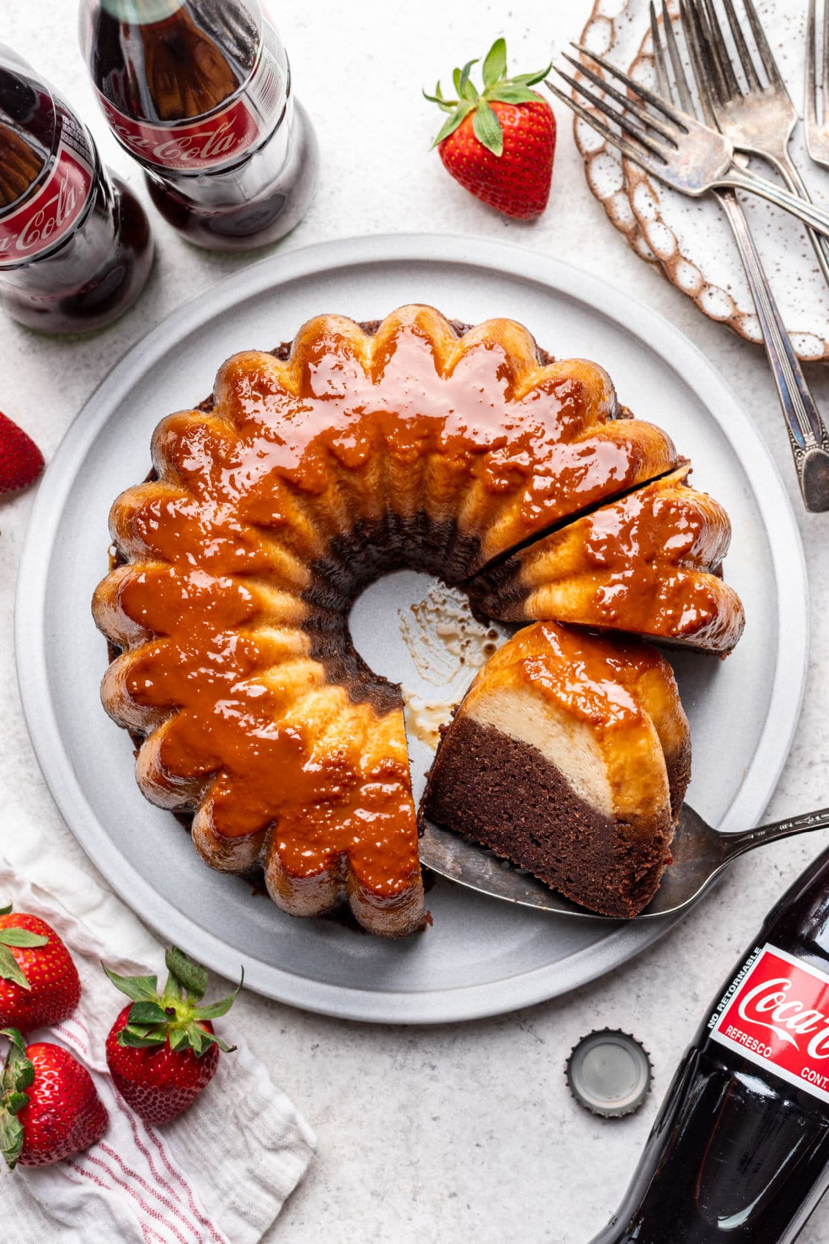 A partially sliced chocoflan on a platter next to Mexican cokes.