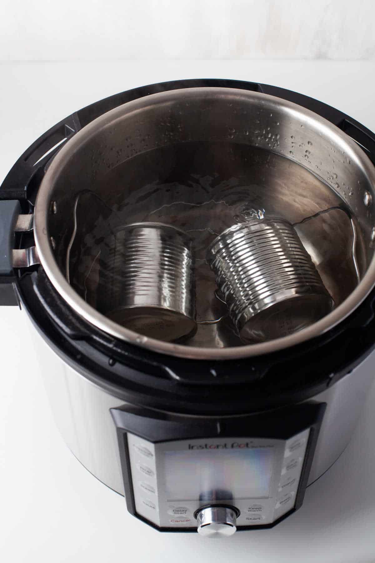 Two cans of sweetened condensed milk covered with water in an Instant Pot. 