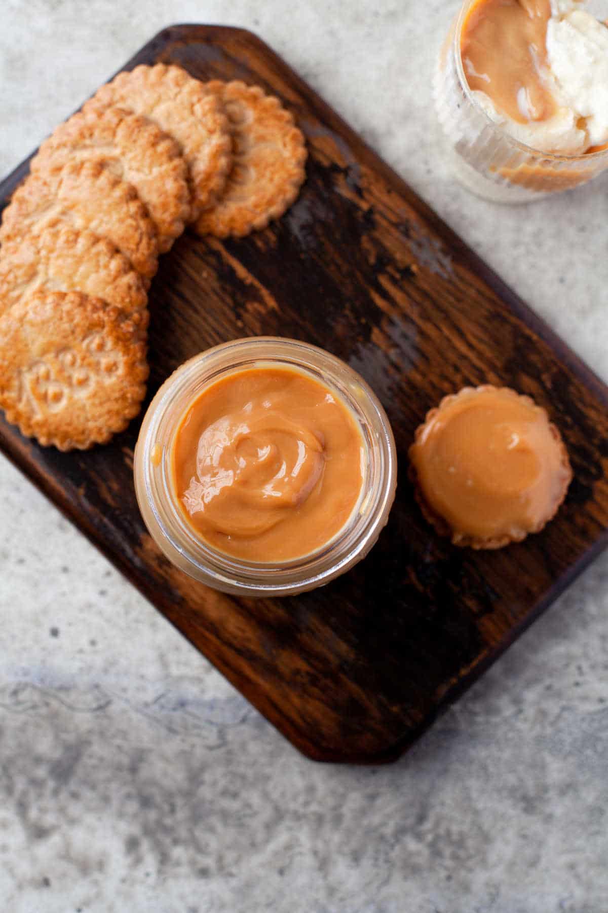 Overhead photo of a jar of dulce de leche next to a row of cookies. 