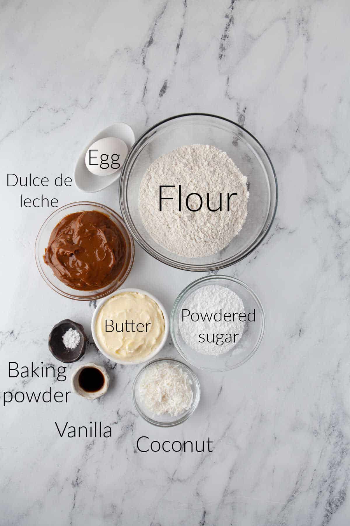 Ingredients for alfajores in dishes with labels on it.