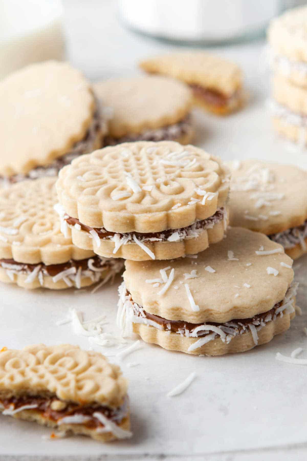 Alfajores stacked on top of each other on a piece of parchment paper.