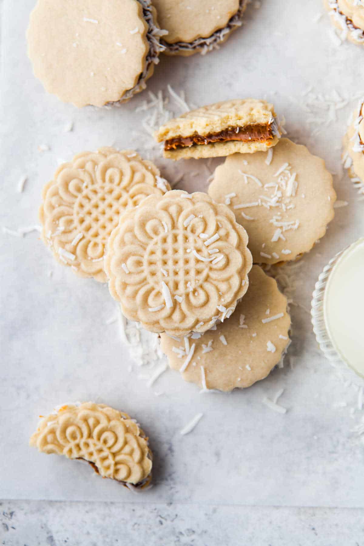 Alfajores on a piece of parchment paper with one broken in half. 