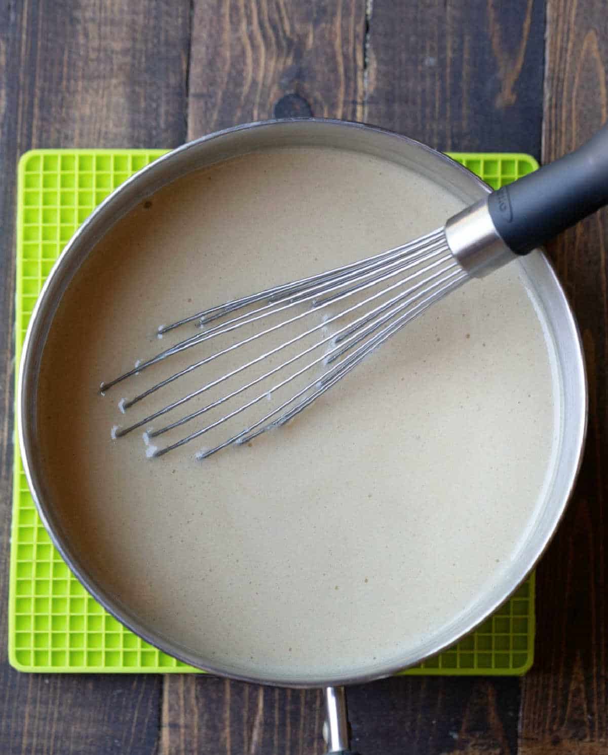 Buttermilk syrup in a saucepan with a whisk in it.