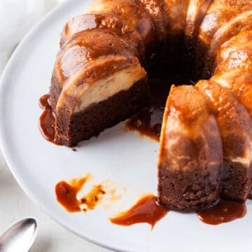 Chocoflan on a white platter with a piece missing.