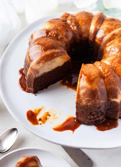 Chocoflan on a white platter with a piece missing.