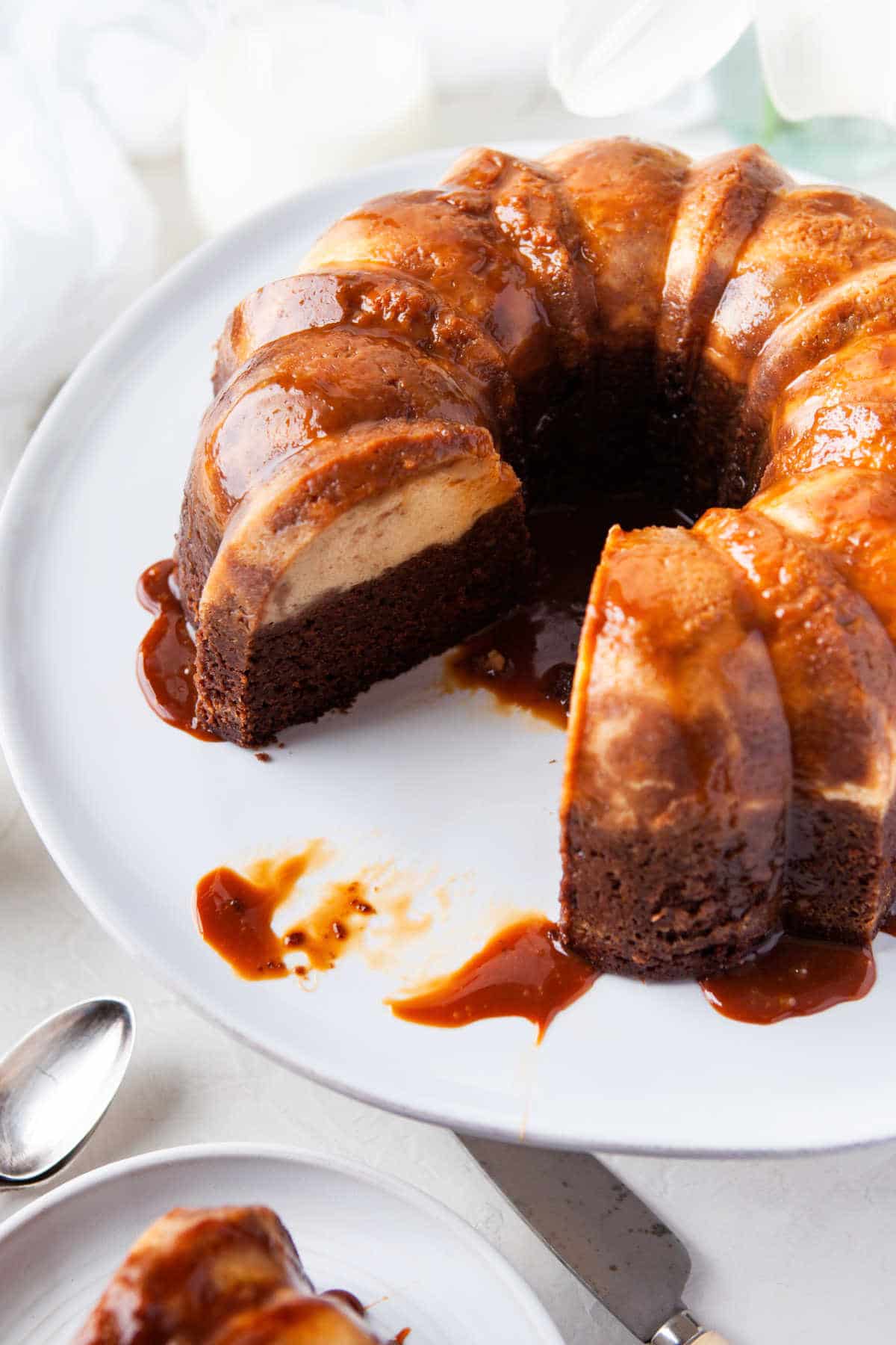 Chocoflan on a white platter with a piece missing. 