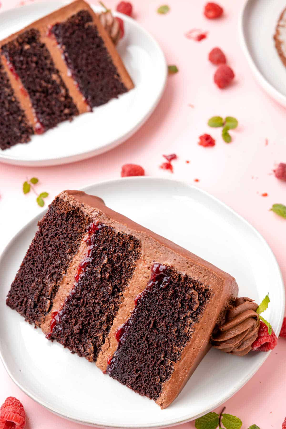 Two slices of chocolate raspberry cake on white plates. 