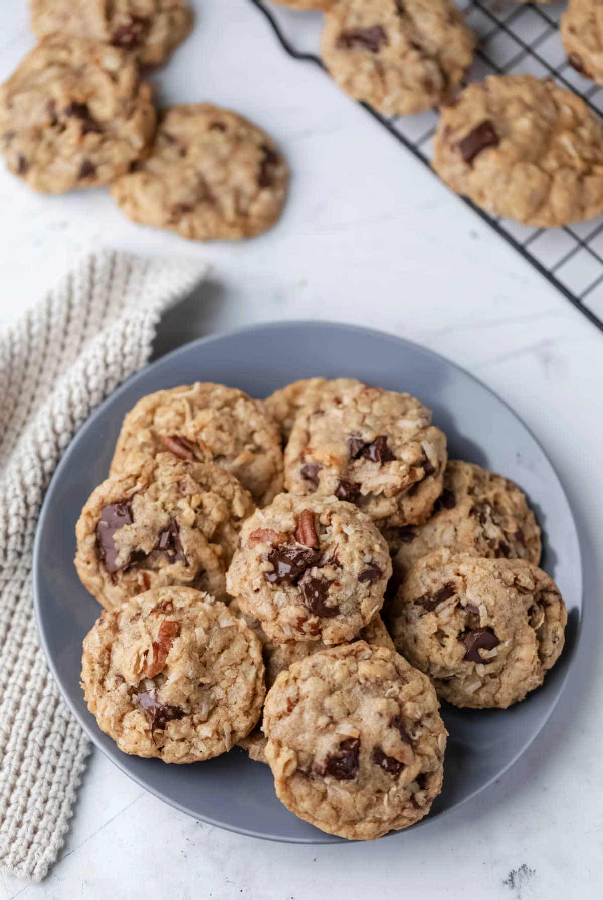 A plate of cowboy cookies next to a wire cooling rack.