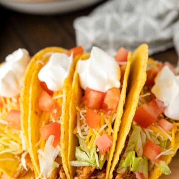 Crock pot chicken tacos on a wooden cutting board.