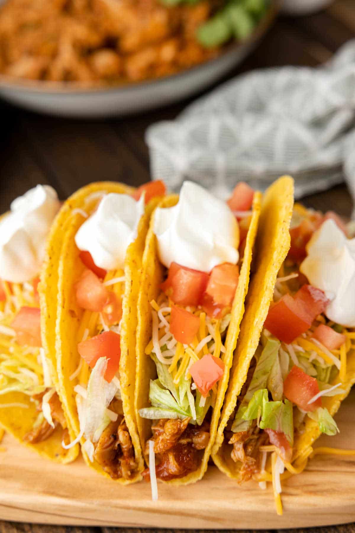 Crock pot chicken tacos on a wooden cutting board. 