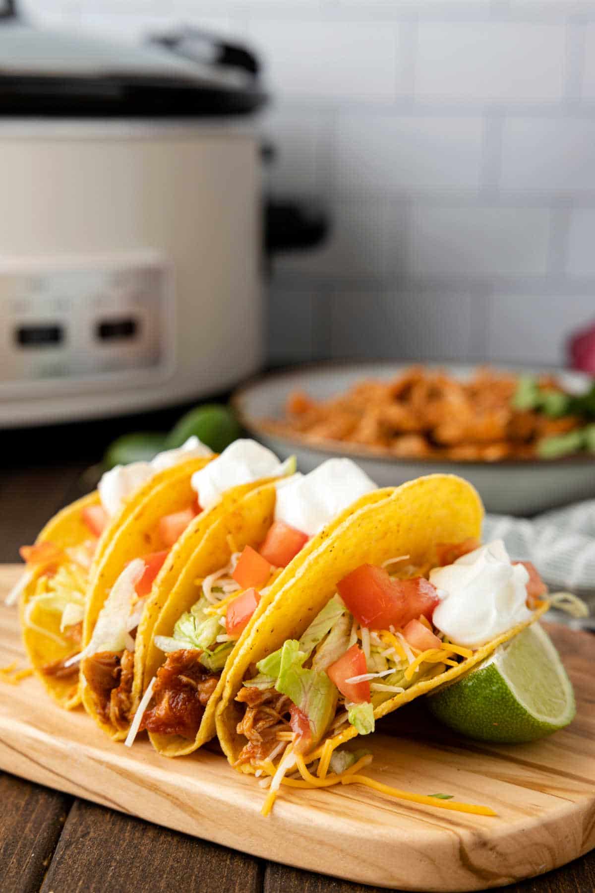 Chicken tacos next to a slice of lime. 