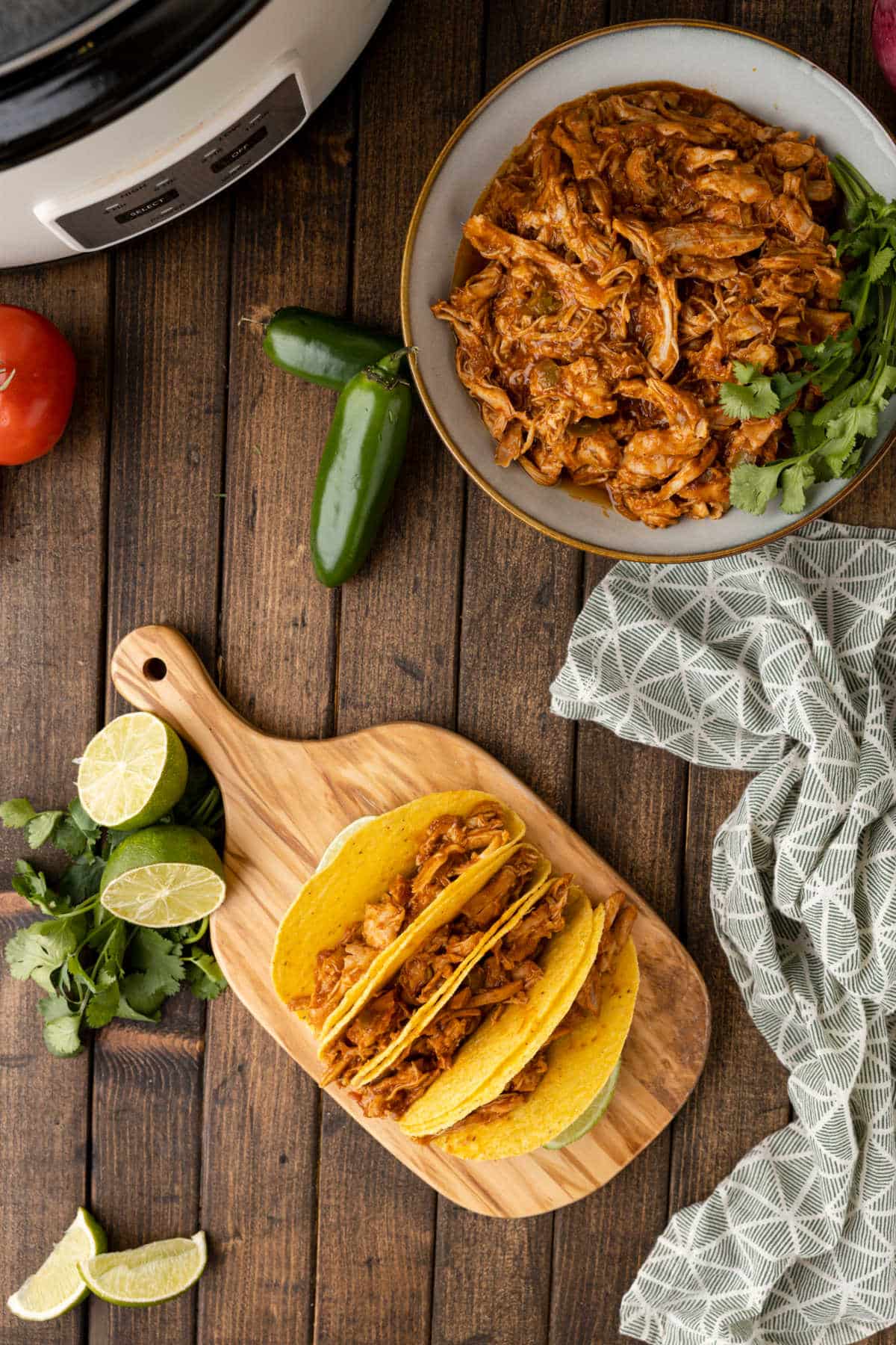 Taco meat in shells next to a dish of shredded taco meat. 