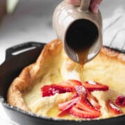Maple syrup pouring onto a German puff pancake.