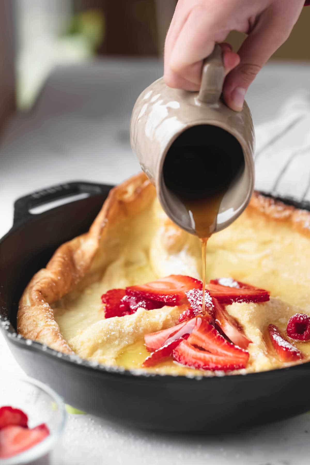 Maple syrup pouring onto a German puff pancake. 