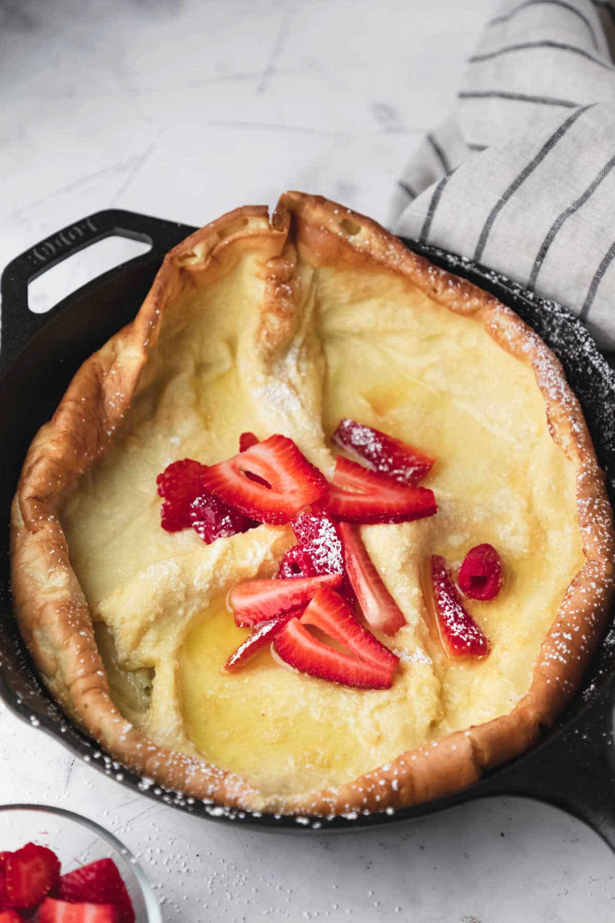 German pancake next to a dish of berries. 