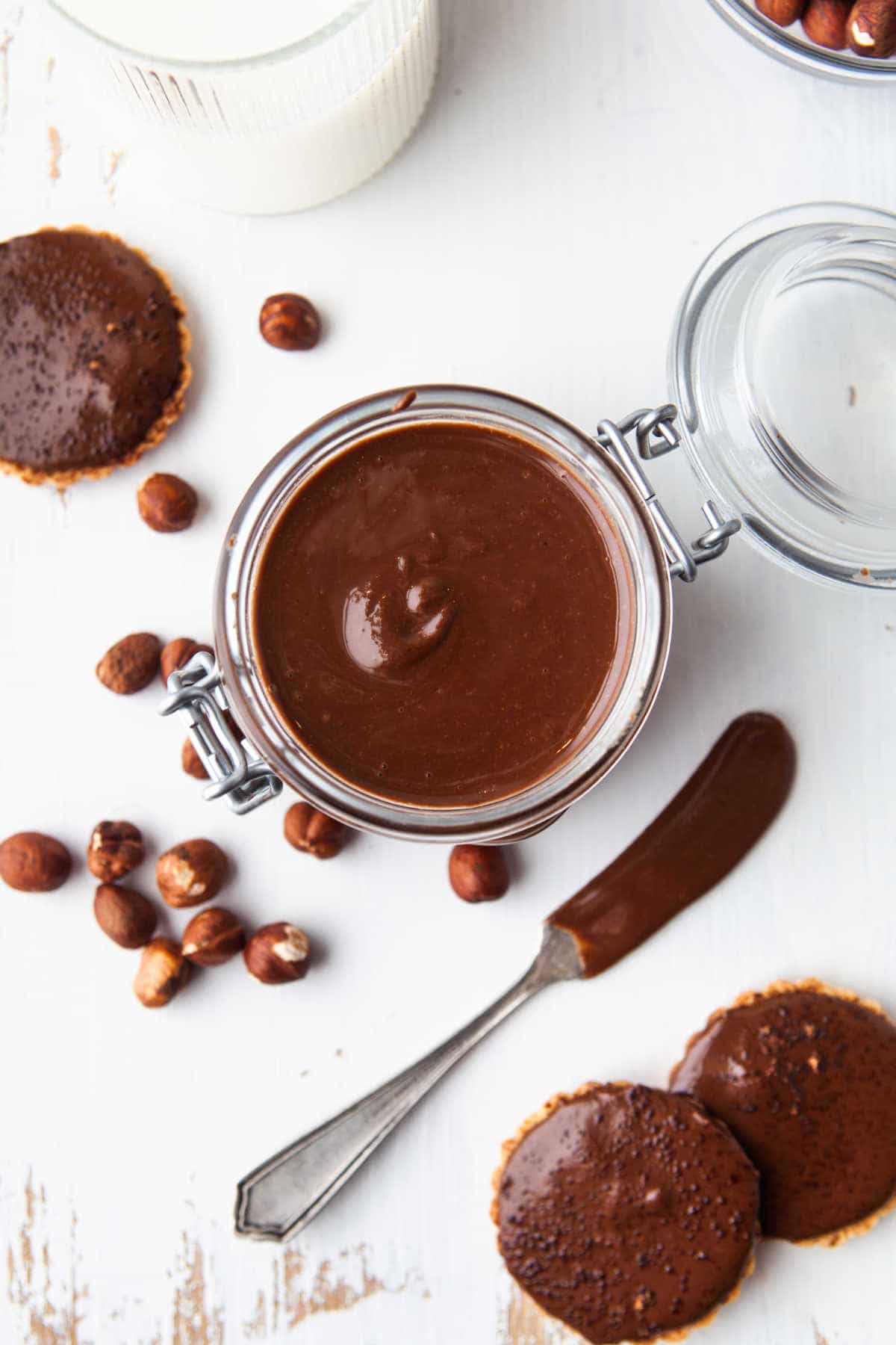 A jar of Nutella next to a glass of milk. 