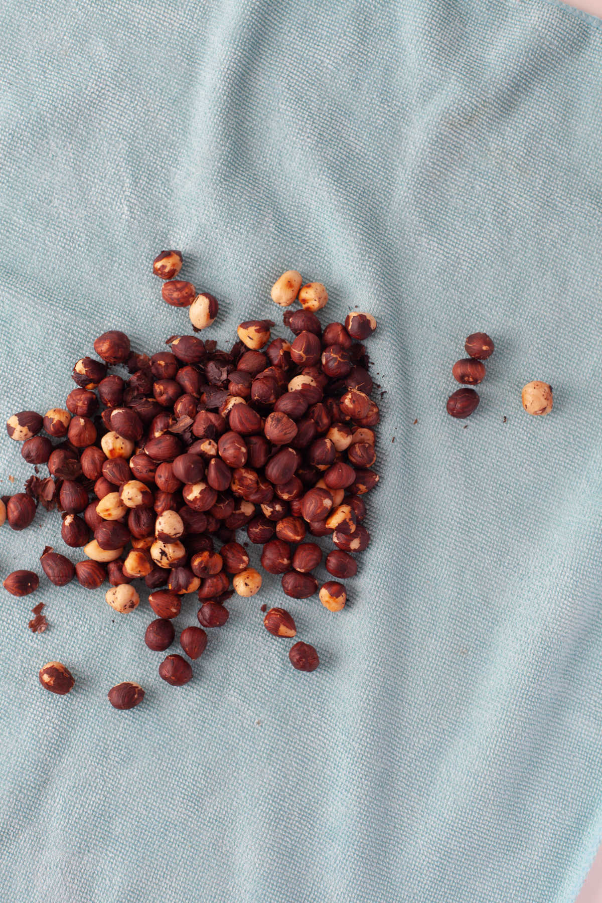 Toasted hazelnuts on a blue kitchen towel. 