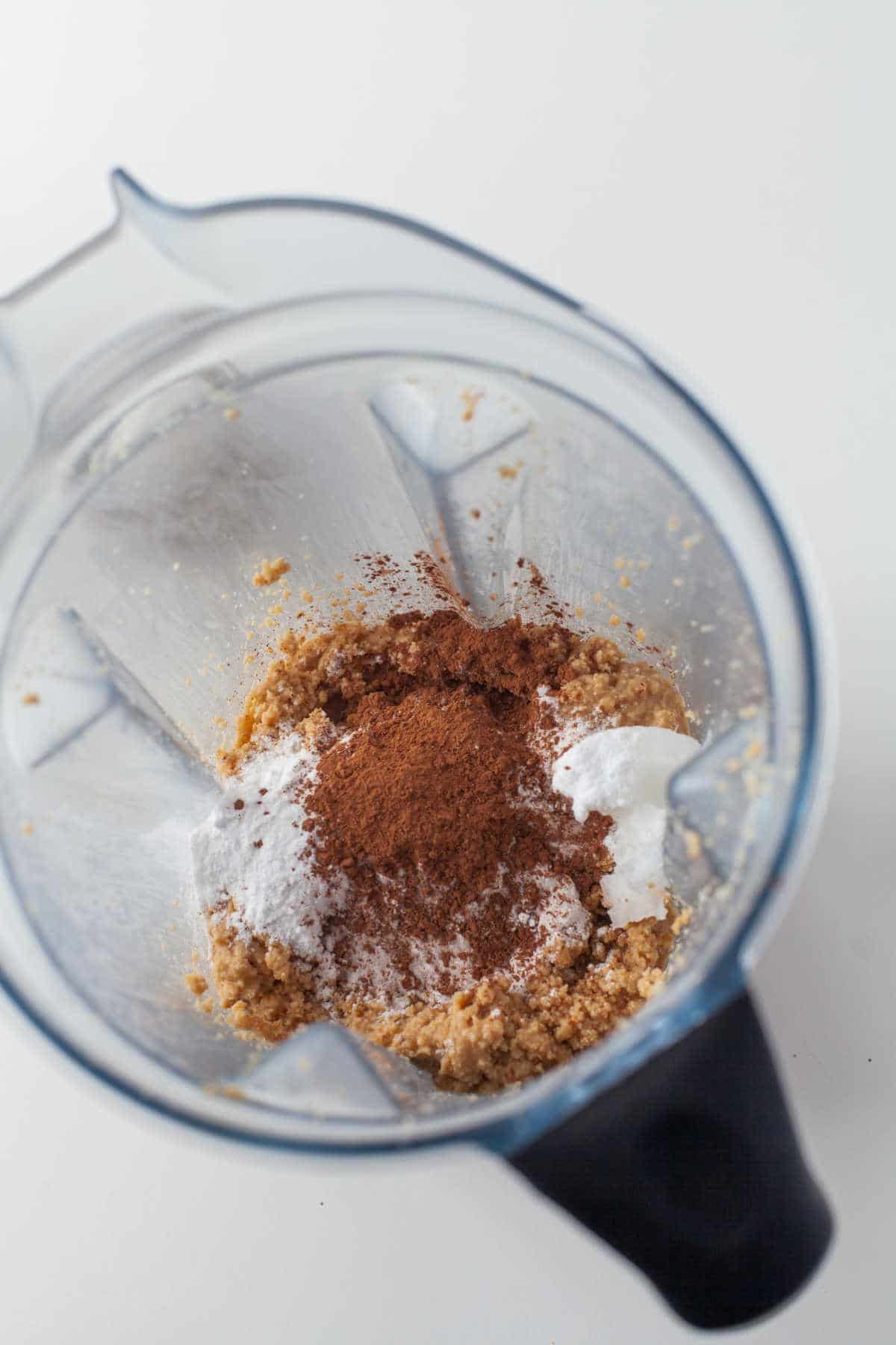 Cocoa powder powdered sugar and coconut oil over blended hazelnuts.