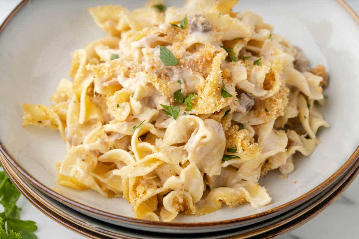 A close up photo of a plate of tuna noodle casserole topped with parsley.
