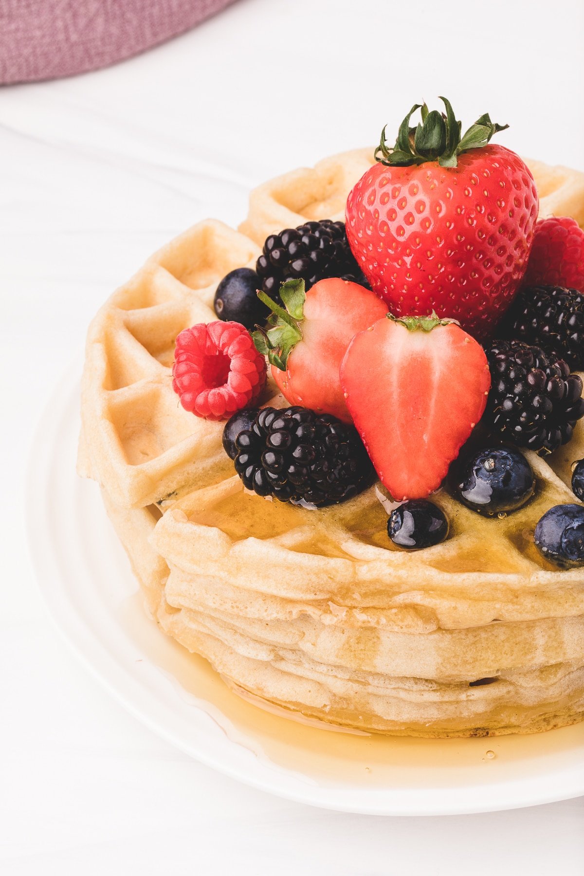 Stack of Belgian waffles topped with fresh berries. 