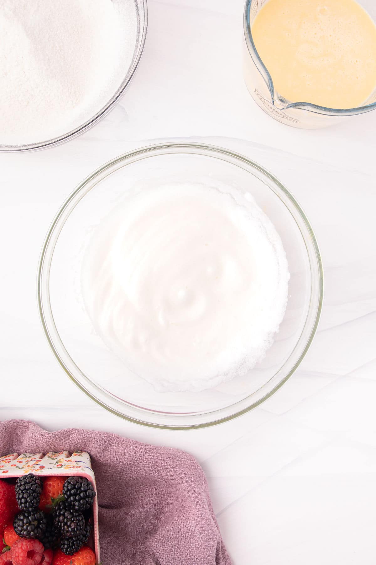 Whipped egg whites in a glass mixing bowl. 