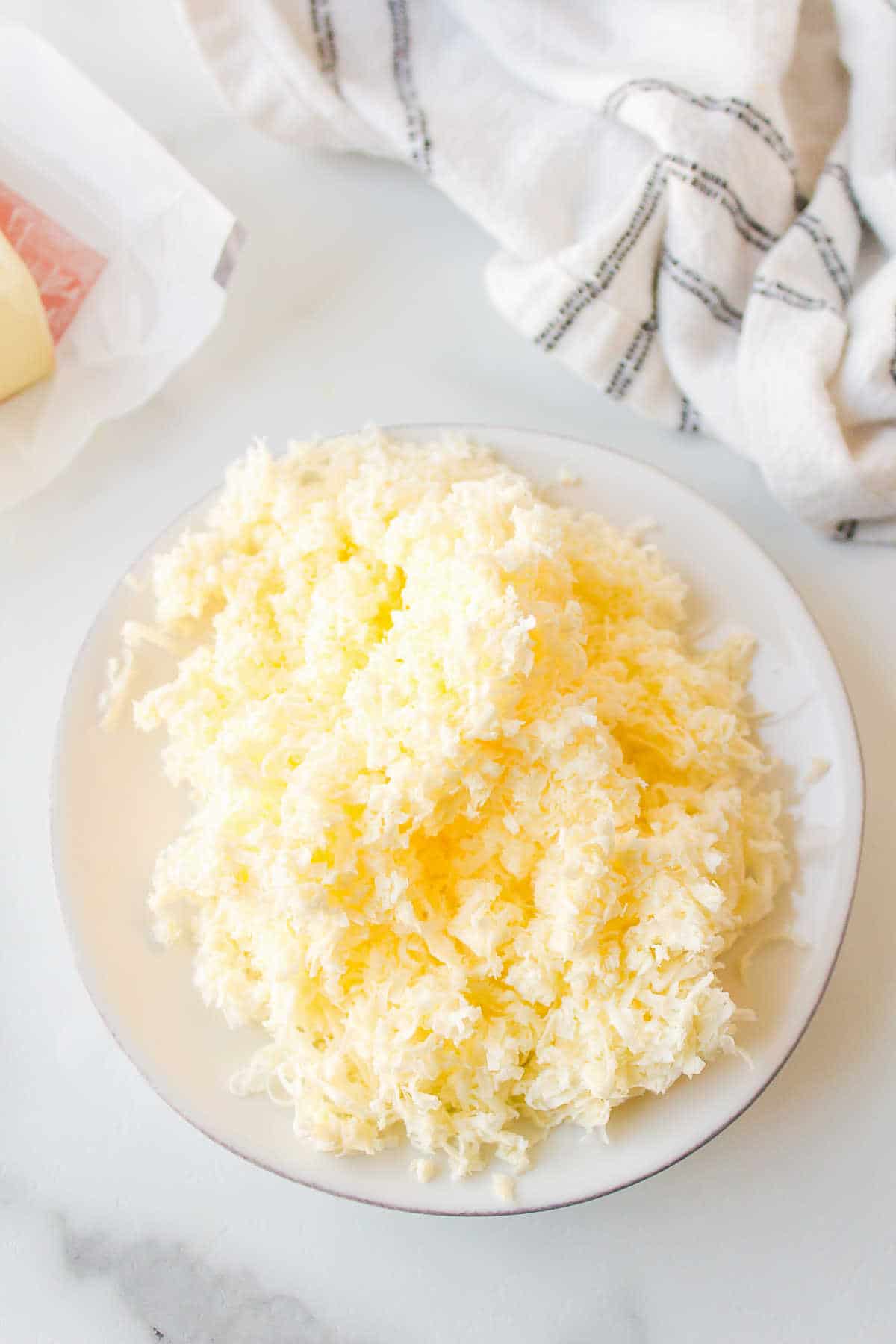 A white plate full of grated butter. 