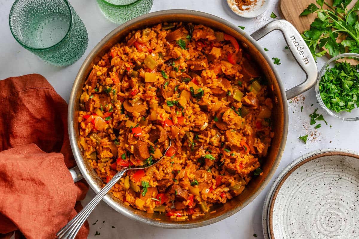 A skillet of Cajun sausage and rice next to an orange napkin.